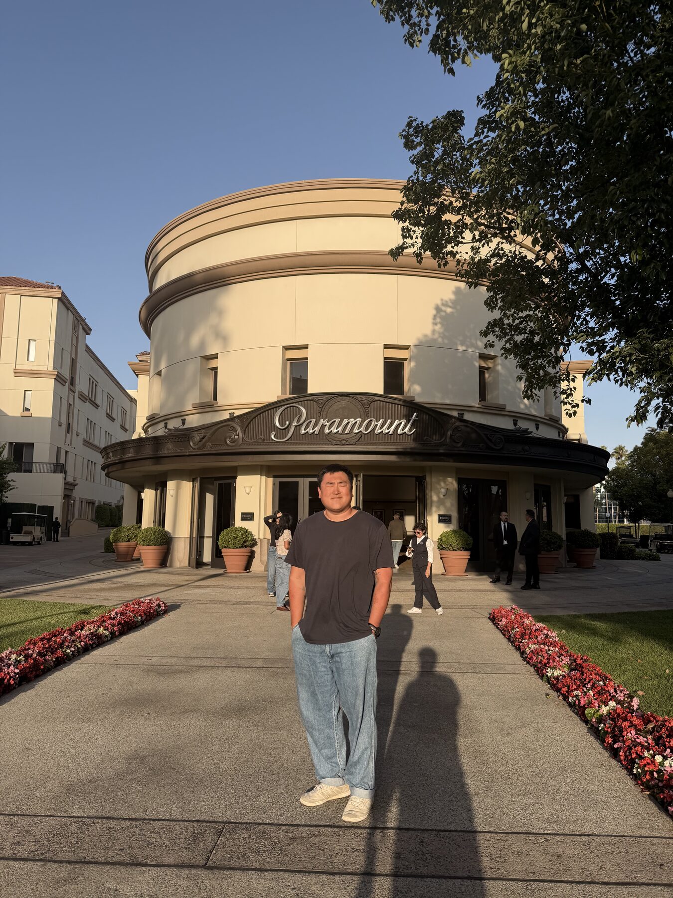 Justin in a gray tee standing on the path in front of the Paramount Theatre marquee at golden hour