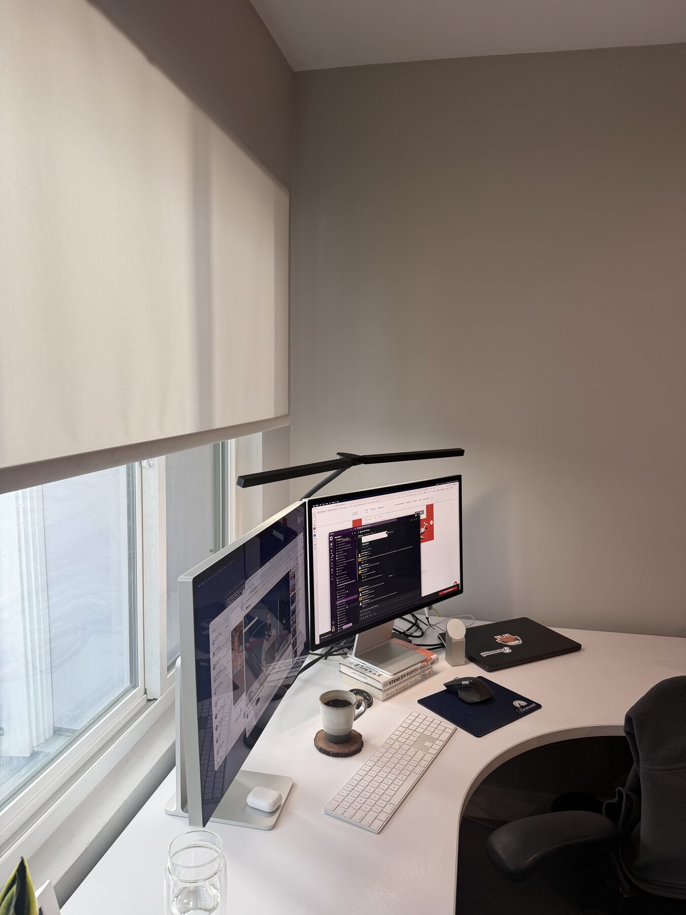 Work station: dual monitors, monitor light bar, mechanical keyboard, ceramic mug, Stanley Kubrick book, Paramount-logo mousepad, blackout shade pulled most of the way down