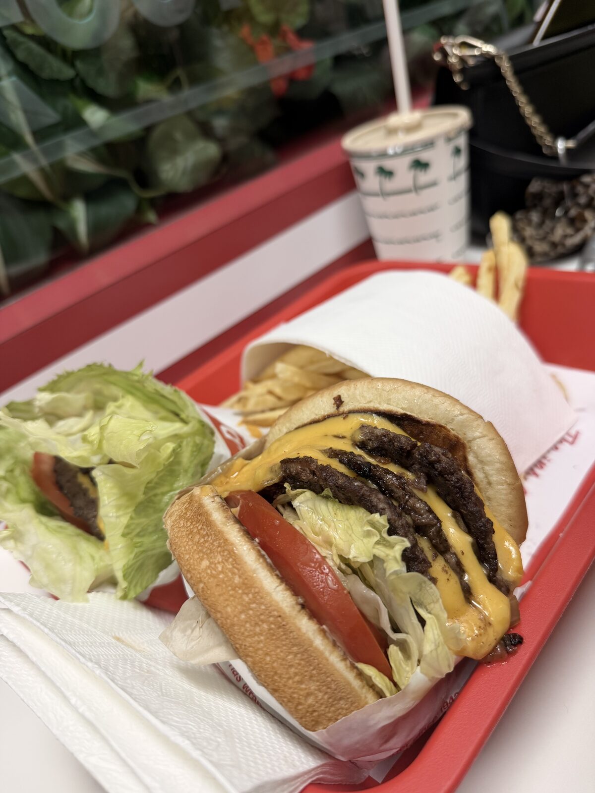 An In-N-Out 4x4 — four patties, four slices of cheese — with fries on a red tray, a protein-style burger beside it